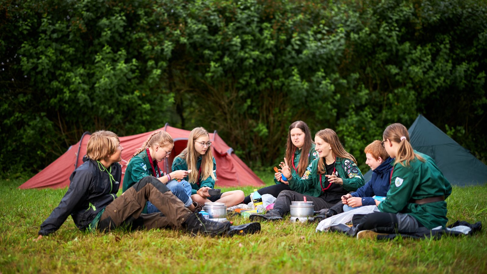 Gruppe af spejdere fra KFUM-Spejderne, der sidder sammen ved orange telte.