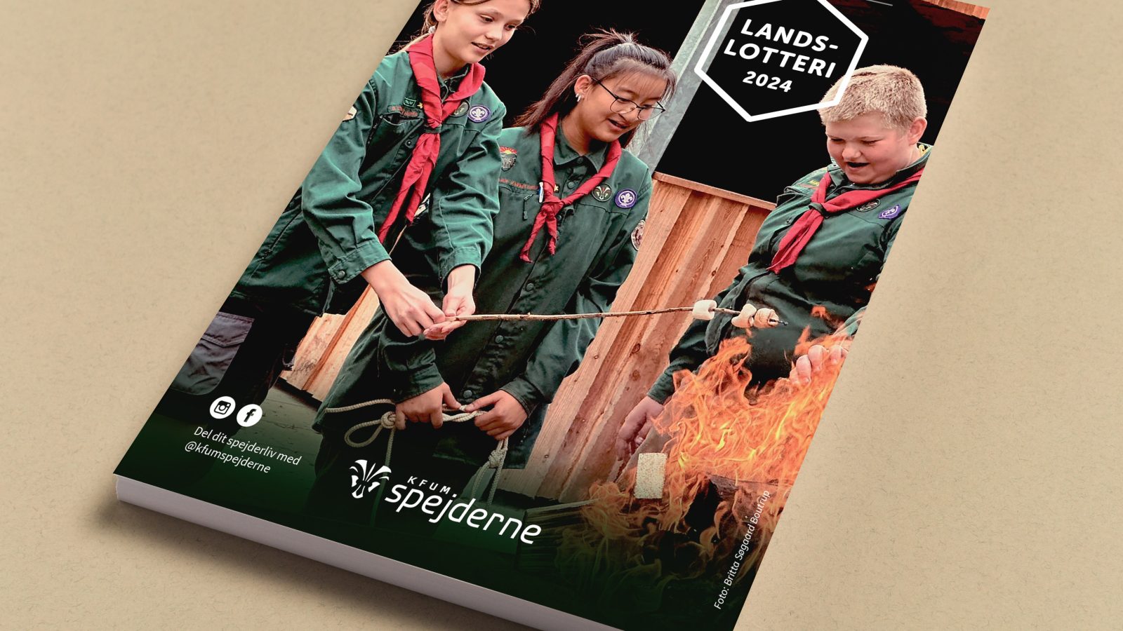 Forside til landslotteri 2024, der forestiller tre børn ved et bål, der rister skumdfiduser.