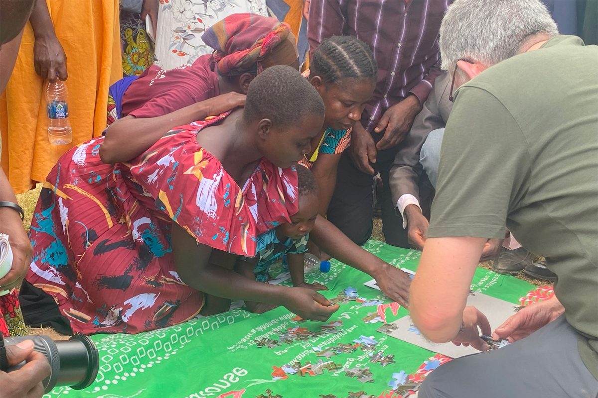 Børn og mand samler et puslespil på et tæppe Malawi 2023