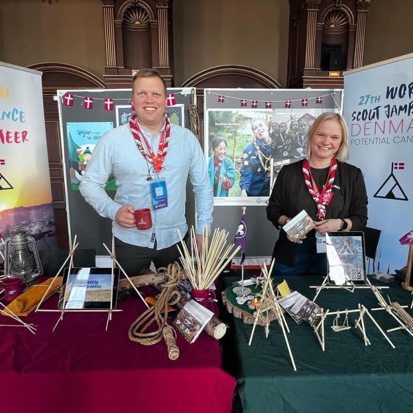 To spejderledere viser en færdselstavle for en gruppe børn