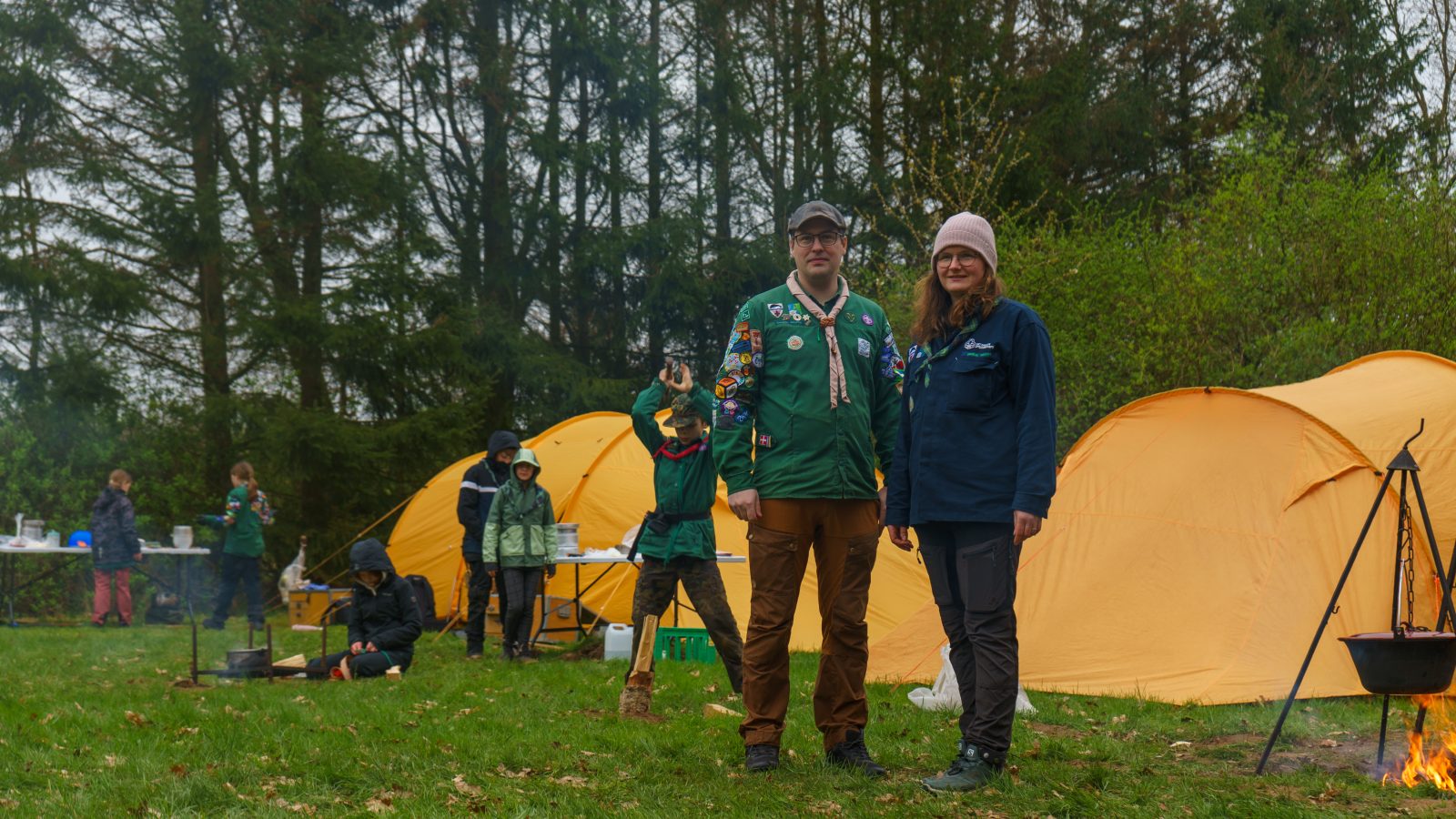 To spejderledere foran orange telte