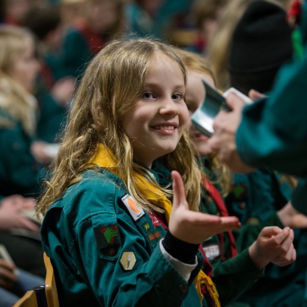 To spejderledere viser en færdselstavle for en gruppe børn