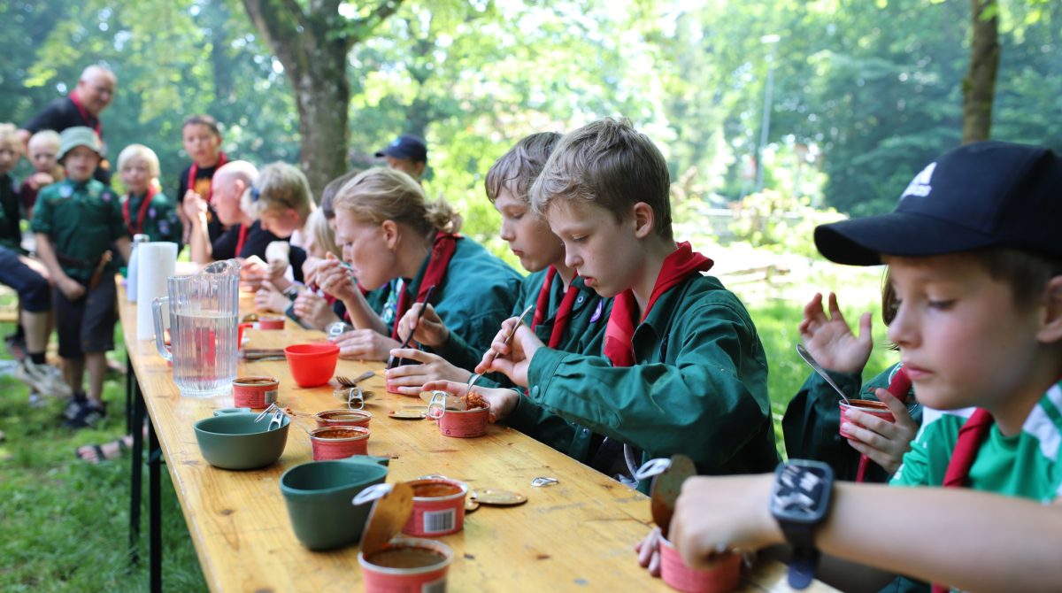 Flammegruppens yngste spejdere spiser makrel på tid ved et bord.
