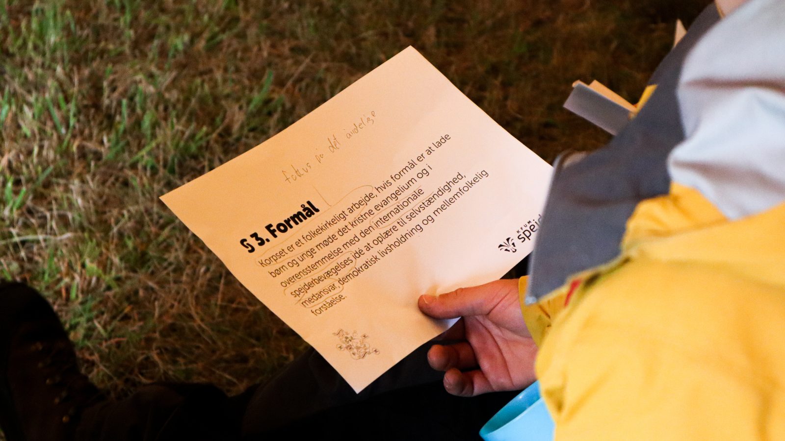Hånd holder papir med KFUM_Spejdernes formål skrevet ned.