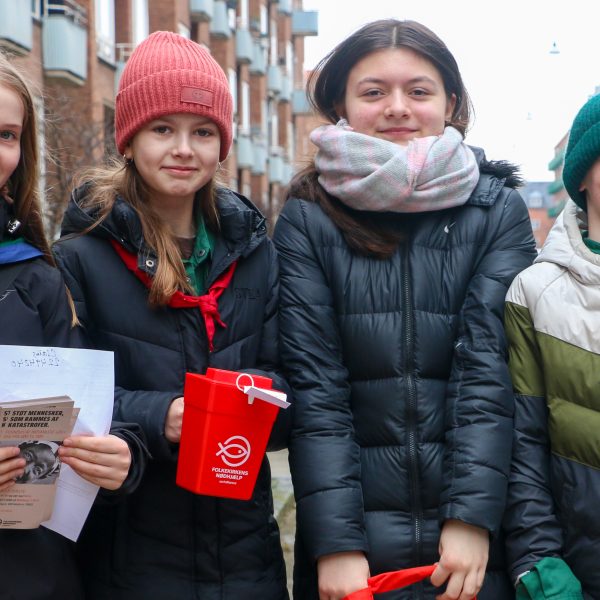 To spejderledere viser en færdselstavle for en gruppe børn