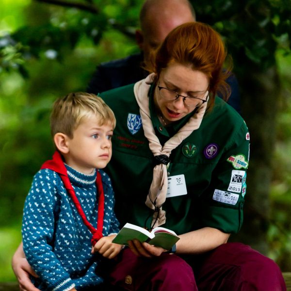 To spejderledere viser en færdselstavle for en gruppe børn