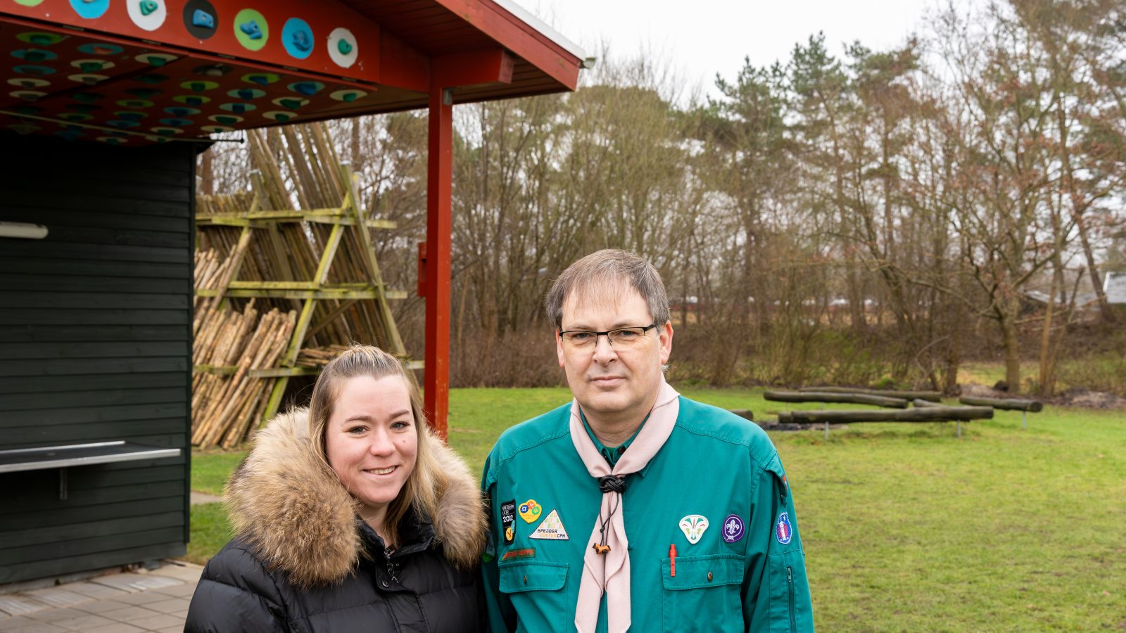 To voksne spejderer står foran gruppens hytte.