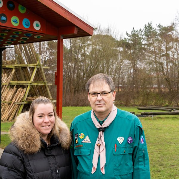 To spejderledere viser en færdselstavle for en gruppe børn