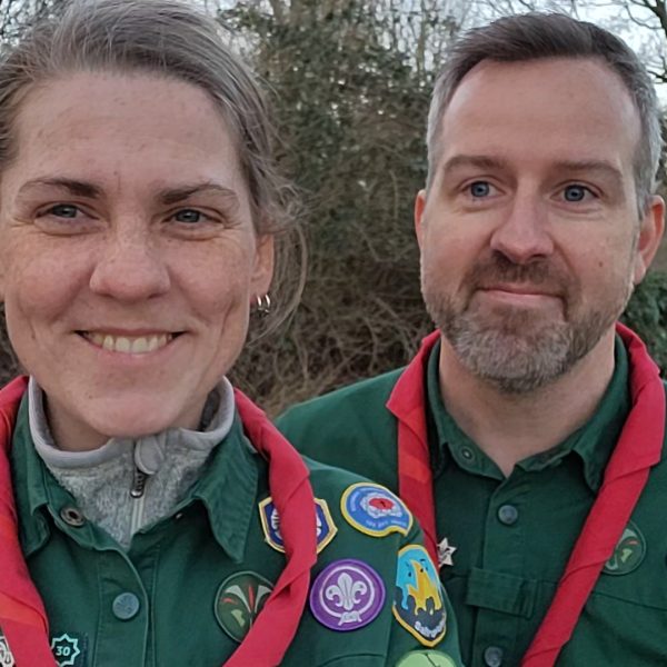 To spejderledere viser en færdselstavle for en gruppe børn