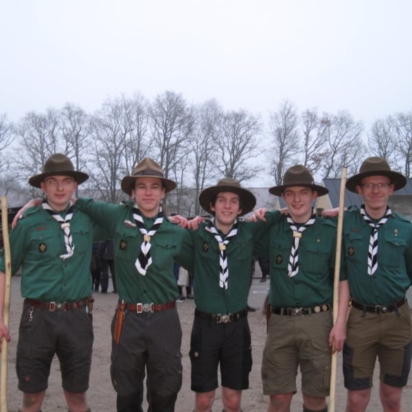 To spejderledere viser en færdselstavle for en gruppe børn