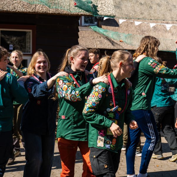 To spejderledere viser en færdselstavle for en gruppe børn